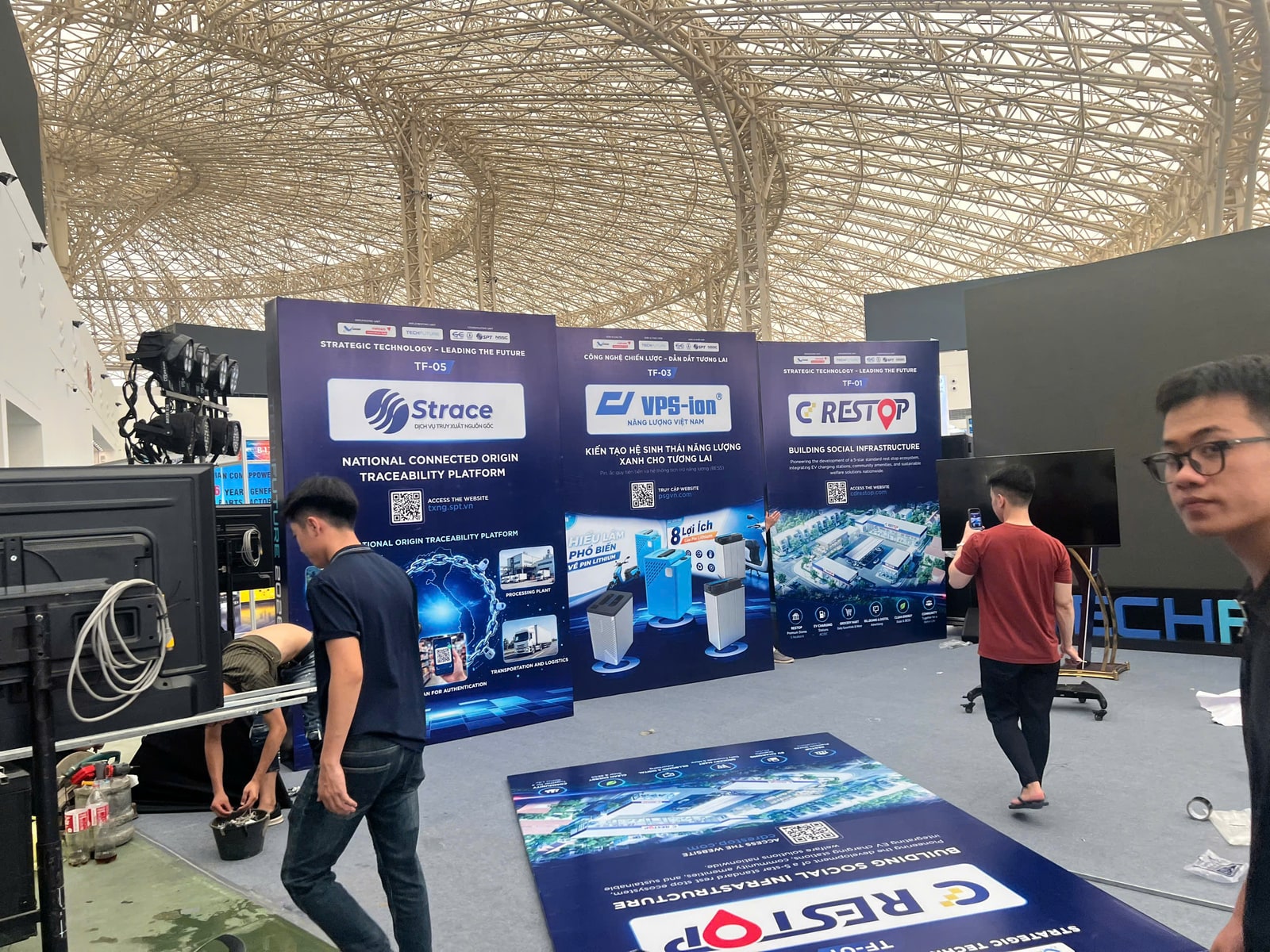 Đội thi công dựng gian hàng công nghệ tại Hall 4 VEC Đông Anh chiều 08.9.2026: ba standee TF-05 Strace, TF-03 VPS-ion, TF-01 CD Restop đã dựng, backdrop CD Restop còn trên sàn